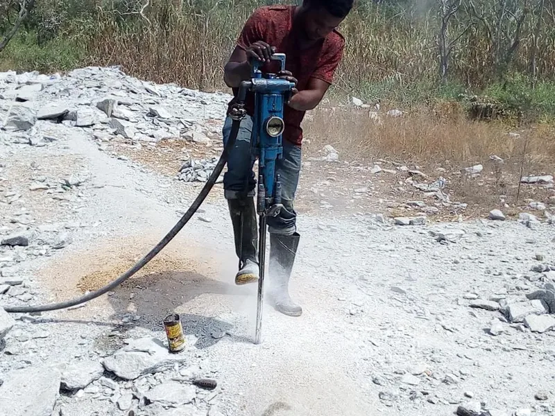 Worker drilling into rock to collect a sample