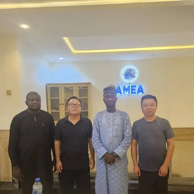 AMEA team with partners in the Kano office beneath the AMEA sign