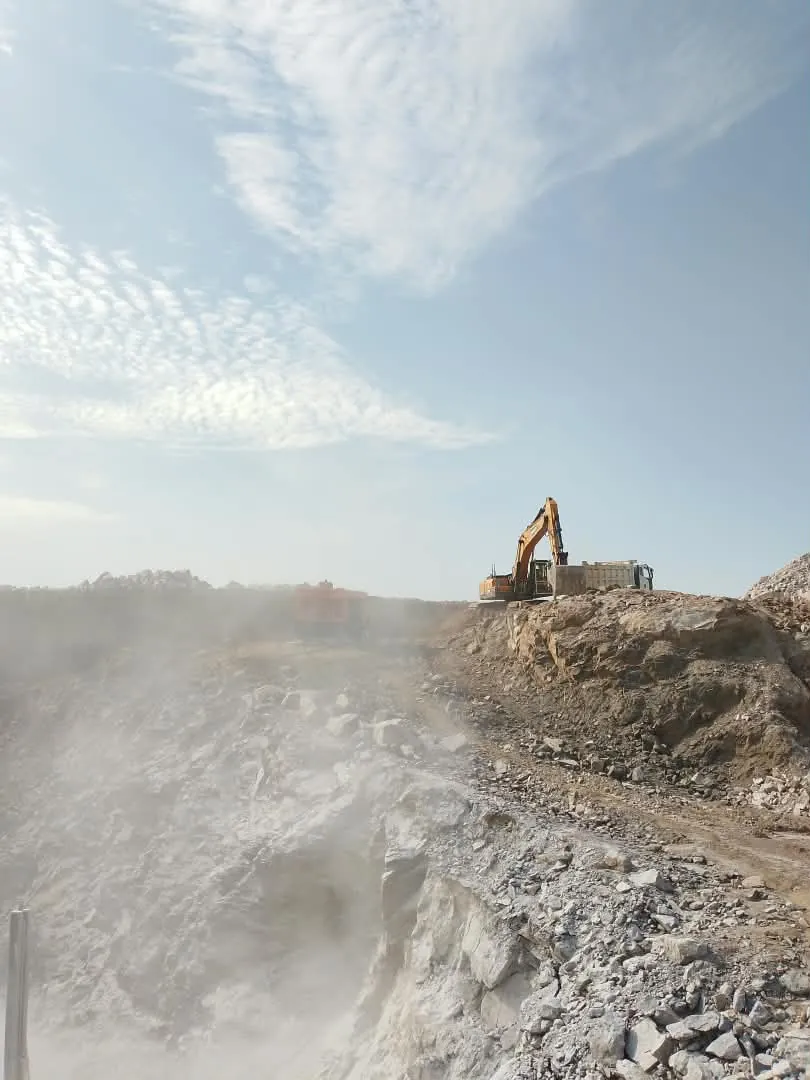 Excavator loading a haul truck on the ridge above the pit